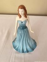 Front view of the figurine showing the woman in a strapless turquoise dress with a blue gem on the chest.