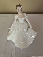 Front view of Royal Doulton Nancy porcelain figurine showing white flowing gown, delicately posed hands, and flower in hair.