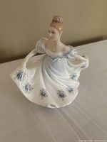 Front-side view of the Royal Doulton 'The Countess' figurine showing the detailed facial features, pink hair bun, off-shoulder blue dress decorated with blue flowers around the skirt.