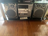 Full photo showing the stereo system main unit with two speakers on each side and the remote control placed in front.