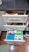 View of kitchen drawers with towels and storage items visible in two drawers