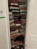 Closet shelving with stacks of assorted towels and linens in various colors and sizes.