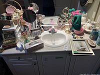 Full view of bathroom counter with assorted bath supplies and decorative items around sink