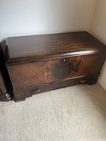 Closed view of the dark wooden Boshart chest on carpeted floor.