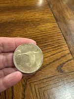 Front of 1982 Canadian dollar coin with flying goose design held in hand showing detailed bird and inscriptions.
