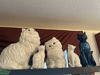 Front view showing the full set of five ceramic cat figurines in white and blue.