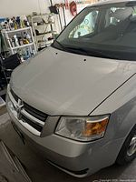 Front driver side view of silver Dodge Caravan SXT showing hood, grille, headlight, and front bumper