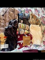 Photo showing multiple folded fleece blankets with prints of a black dog, a tiger, and some plain colors, with some blankets still in original tags or packaging