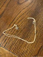 Gold chain necklace with flower charm laid flat