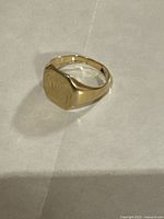 Front view of signet ring showing shield-shaped face and monogram engraving