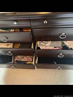 Open drawers showing neatly folded various ladies clothing such as sweaters and socks in dark brown furniture.