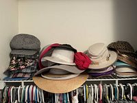 Overview of hats arranged on a closet shelf including straw sun hats, patterned caps, and some with decorative bands.