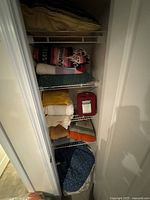 View of closet interior showing stacked towels, sheets, blankets, and the red Cannon microflannel sheet set package.