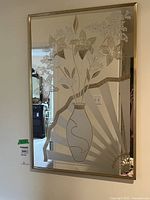 Full view of the framed mirror showing painted floral design including a vase with flowers and leaves, geometric pattern accents, gold-tone frame.