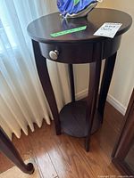 Image showing the entire plant stand with drawer and lower shelf against a wall near a window.