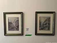 Two framed vintage urban scene prints hanging side by side on a wall, showing overall condition and framing.