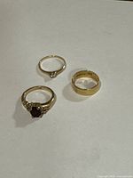 Three yellow gold rings displayed together on light background