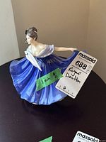 Full side view of the lady figurine showing blue flowing dress and hand fan