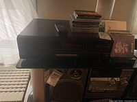 Full view of Technics SL-PG580A CD player with remote and stack of CDs on top, sitting above a vintage stereo system.