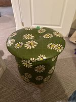 Side and top view of the vintage vinyl storage ottoman with green daisy pattern, showing overall condition and size.