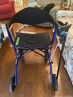Front view of blue Excursion walker showing seat, black backrest, front wheels, and cane holder with grabber on right side.