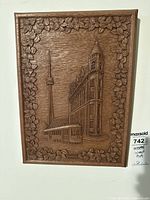 Front view of wood carving plaque showing Gooderham Building, CN Tower, streetcar and leaf border