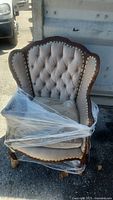 Front view of tufted armchair wrapped in plastic