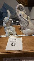 Both ceramic elephant figurines on box top showing size tape and lot number