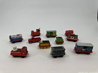 Photo showing all 11 toy cars and trains arranged on a white surface with clear distinction of colors and details.