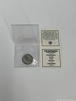 Top view of 1942-45 silver nickel coin in plastic protective case with two informational cards describing the coin's silver content and specifications.
