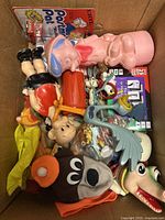 Box containing various vintage plastic toys and hand puppets including Porky Pig, Bugs Bunny, Road Runner and brown dog puppet.