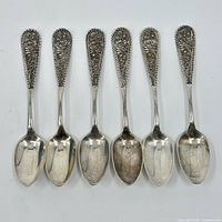 Top view of 6 identical sterling silver spoons with filigree handles arranged side by side, showing the bowls and handles with intricate openwork designs.