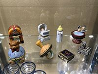 Overview of 8 small decorative items displayed on glass shelf