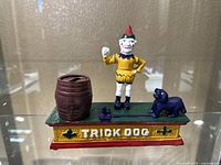 Front view of the full Trick Dog cast iron mechanical bank including figure, dog, barrel, and base.
