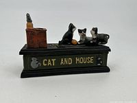 Front angle of the cast iron cat and mouse mechanical bank showing the cat and mouse figures, chimney, and side text.