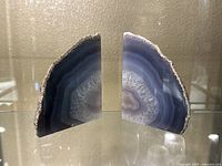 Front view of pair of cut agate stone bookends showing polished, banded blue/gray interior and rough exterior edges.