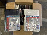 Box with unopened Bi-Directional photo albums holding up to 300 photos each, black and white covers.