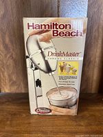 Front view of Hamilton Beach DrinkMaster Chrome Classic mixer box showing the mixer in use with a creamy drink.
