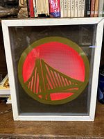 Front view of the framed Golden State Warriors logo sign illuminated in red.