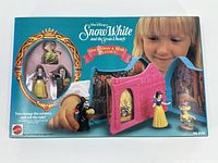 Front view of original boxed Mattel Snow White and the Seven Dwarfs Once Upon a Time Playset. The box shows the fold-out book style pink castle with Snow White figurine and Evil Queen, plus other dwarfs. Child shown demonstrating playset.