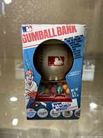 Front view of boxed MLB vintage gumball bank featuring baseball design, MLB logo, and promotional text.