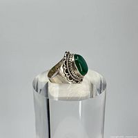Front angle view of silver ring with green chrysoprase stone on clear acrylic stand.