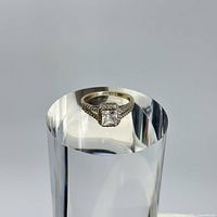 Close-up photo of the sterling silver ring showing the square cut quartz center stone and textured band details on a reflective surface.