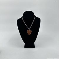 Full view of the silver chain necklace displayed on a black bust showcasing the heart-shaped brown glittery pendant.