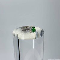 Ring displayed on clear cylindrical stand highlighting profile and stone details