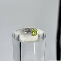 Top perspective of sterling silver ring with oval light green stone on display stand.