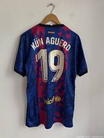 Backside of the blue and red patterned Nike FC Barcelona soccer jersey showing 'KUN AGUERO' and number 19.