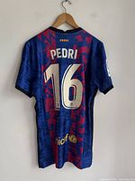 Back view showing Pedri 16 name and number, plus sponsors and logos on bottom back
