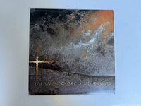Front cover of one vinyl record album titled 'Japan Exorcising Ghosts' with dark and textured artwork and a golden cross design.