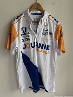 Front view of white IndyCar racing jersey with Journie Rewards branding, multiple sponsor logos, and autograph on the chest area